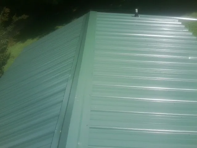 New green metal panels meeting at the ridge of a roof — Flat Roof Repair work by our crew in Panacea