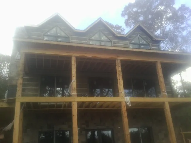Dormers and porch framing on a large log home under construction — Roof Coating work by our crew in Panacea