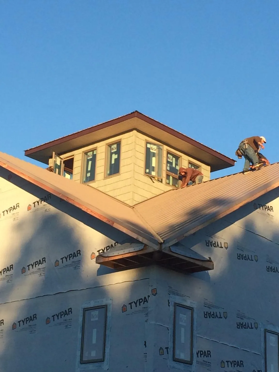 Roofers working around a rooftop cupola on a new metal roof at sunset — Roof Waterproofing in Panacea by Roofing Brothers